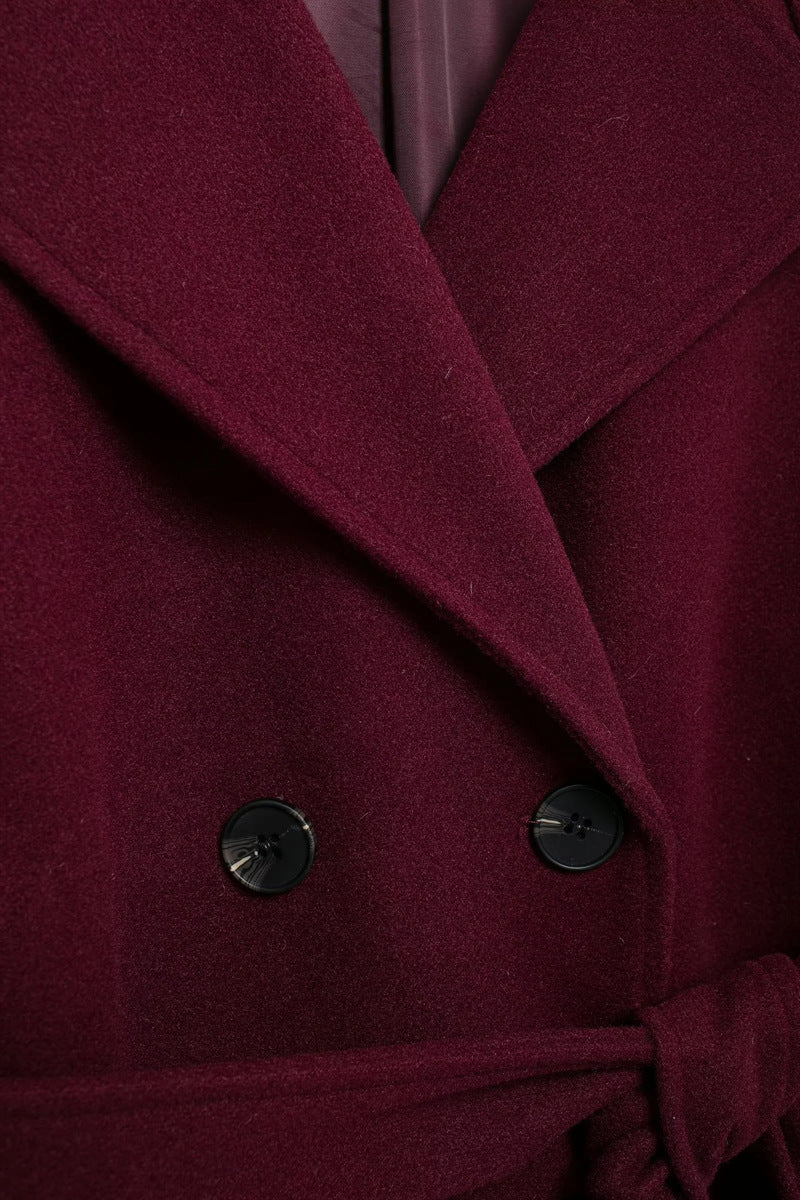 Elegant burgundy vinterjacka med dubbelknappar och bälte.