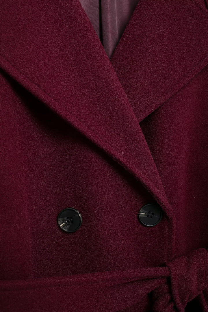 Elegant burgundy vinterjacka med dubbelknappar och bälte.
